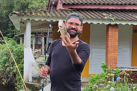 Beto apontando para um arco-íris sobre o jardim da pousada